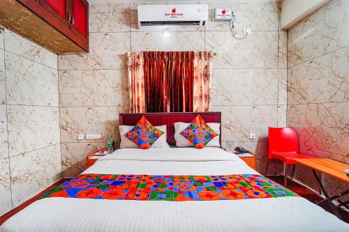 a bedroom with a bed and a red chair at FabExpress Apple Grand Gandhipuram in Coimbatore