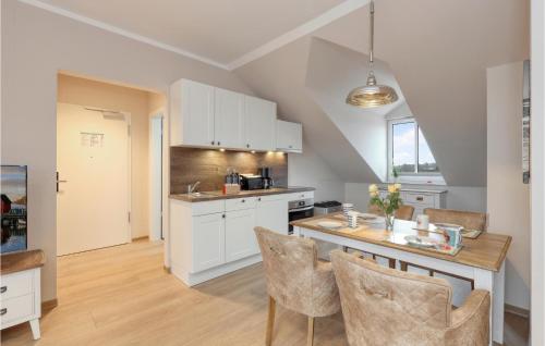 a kitchen with white cabinets and a table with chairs at Baltischer Hof Apartment 65 in Boltenhagen
