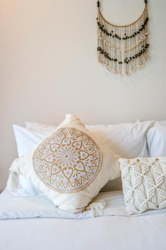 a bed with white pillows and a brown and white pillow at Villa Asri Nusa Dua in Nusa Dua