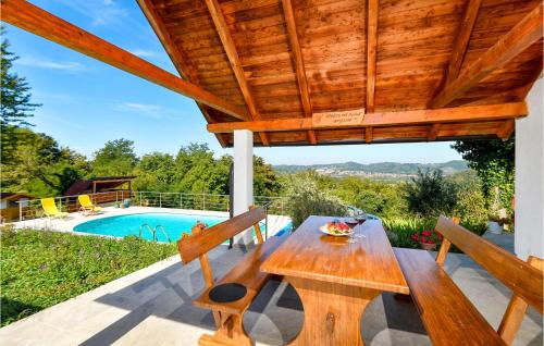a wooden table and chairs on a patio with a pool at 3 Bedroom Beautiful Home In Piscanovec in Tuhovec