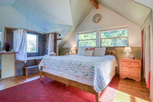 a bedroom with a large bed and two windows at Dream Sea Chalet in Yachats