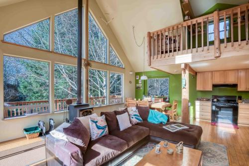 a living room with a brown couch and some windows at Dream Sea Chalet in Yachats