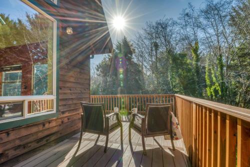 two chairs sitting on a deck with the sun shining at Dream Sea Chalet in Yachats