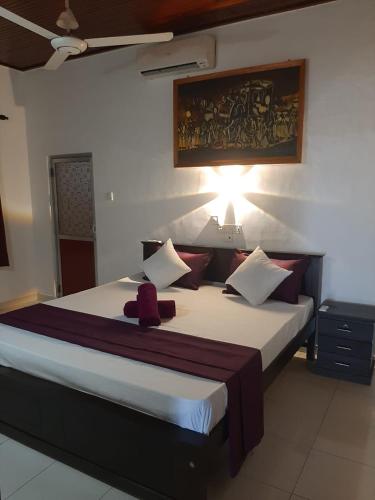 a bedroom with a large bed with a red object on it at Fionn's Coconut Beach House in Negombo