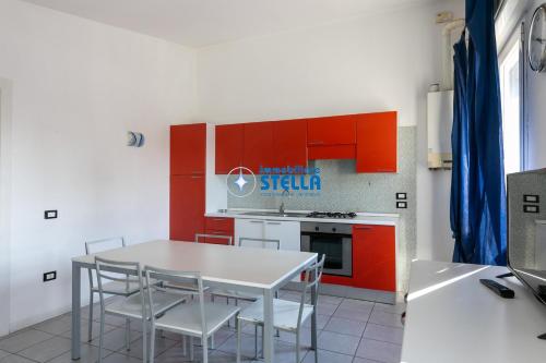 a kitchen with red cabinets and a white table and chairs at Condominio Milan in Lido di Jesolo