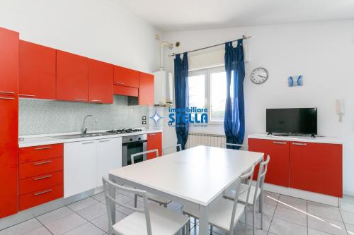 a kitchen with red cabinets and a white table at Condominio Milan in Lido di Jesolo
