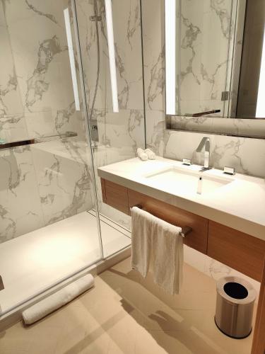 a bathroom with a shower and a sink and a mirror at 2BD Luxury Opera District Apt Downtown in Dubai