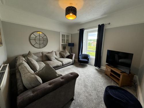 a living room with a couch and a television at Riverside Retreat in Hawick