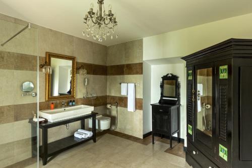 a bathroom with a sink and a toilet and a chandelier at Fort Tiracol Heritage Hotel in Arambol