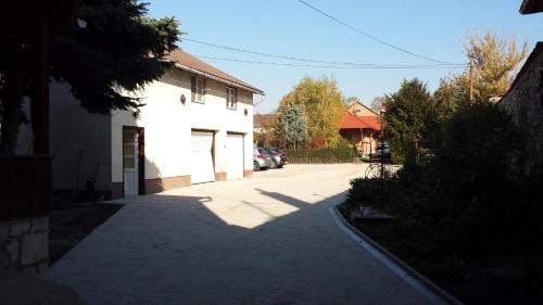 a parking lot with a white building and a driveway at Hattyú Fogadó in Tata