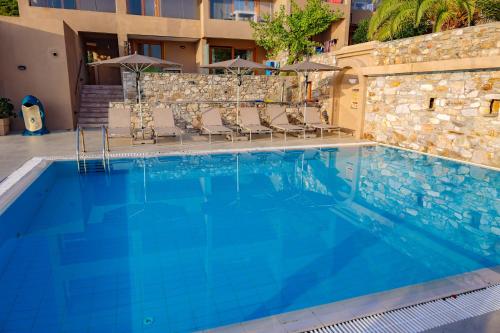 a large blue swimming pool with chairs next to a building at Cape Kanapitsa Hotel & Suites in Kanapitsa