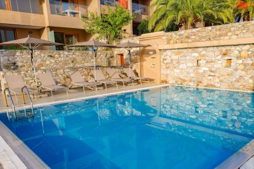 a swimming pool with chairs and umbrellas next to a building at Cape Kanapitsa Hotel & Suites in Kanapitsa