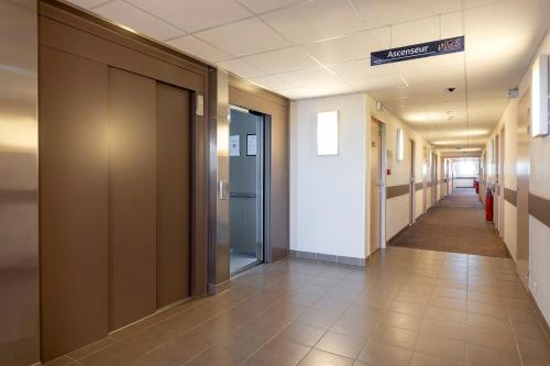 a hallway of an office building with a long corridor at Ace Hôtel Paris Sud Villabe in Villabé