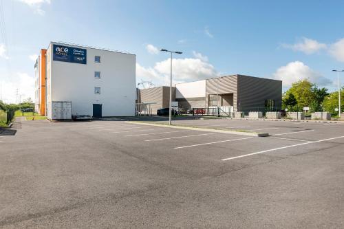 a parking lot in front of a building at Ace Hôtel Paris Sud Villabe in Villabé