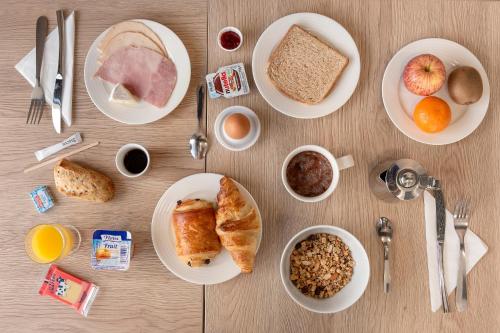 a table with plates of breakfast food on it at Ace Hôtel Paris Sud Villabe in Villabé
