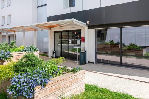 a building with flowers in front of a building at Ace Hôtel Paris Sud Villabe in Villabé