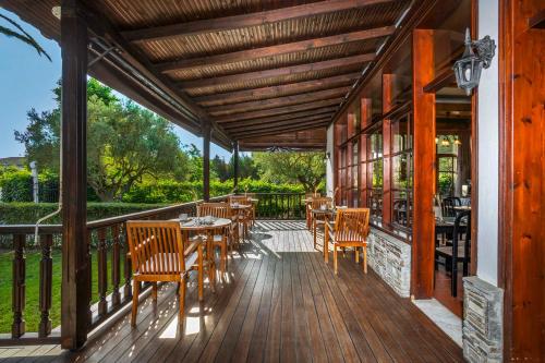 a wooden deck with tables and chairs on it at Hotel Hanioti Village Spa in Hanioti