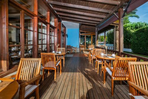 a restaurant with wooden tables and chairs on a deck at Hotel Hanioti Village Spa in Hanioti