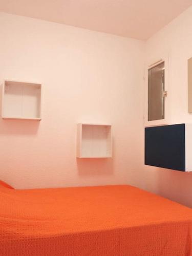 - une chambre avec un lit orange et 2 fenêtres dans l'établissement Appartement - Saint-Cyprien, à Saint-Cyprien