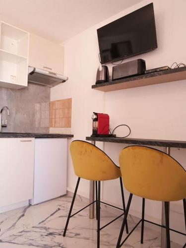 une cuisine avec deux chaises et une table avec un comptoir dans l'établissement Appartement - Saint-Cyprien, à Saint-Cyprien