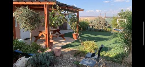 a garden with a wooden pergola and a picnic table at avraham B''H in Nevatim