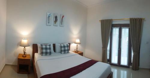a bedroom with a bed with two lamps and a window at Gapul Penida in Nusa Penida
