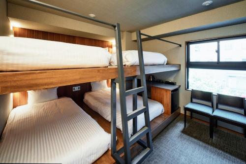 a bedroom with two bunk beds and a window at &HOTEL HAKATA in Fukuoka