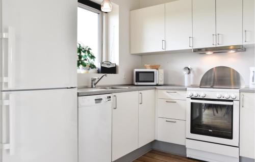 a white kitchen with white cabinets and a microwave at Holiday Home Dyrefolden Ringkøbing Vi in Hee