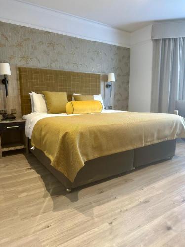 a bedroom with a large bed with a yellow blanket at Hotel Coco in Felixstowe