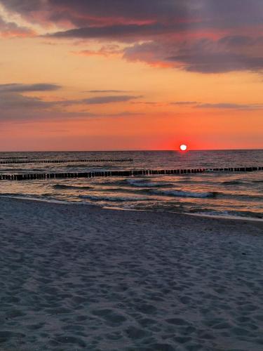 a sunset over the ocean with a pier at App 6 BugOase Ferienwohnung am Bug für 7 Gäste in Dranske