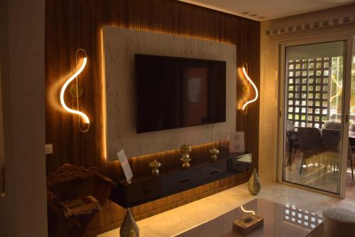 a living room with a television on a wall at Magnifique appartement à Riad Garden in Marrakech