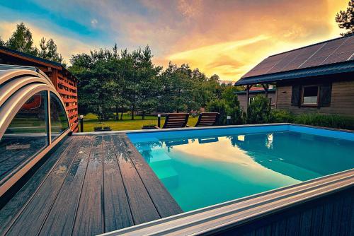 a swimming pool with a wooden deck next to a house at Winiec Family Houses in Winiec