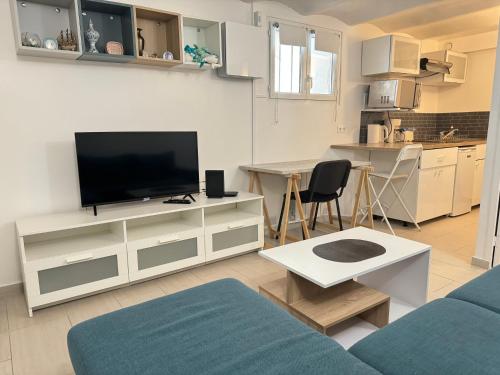Una sala de estar con un televisor, un sofá y una mesa. en Charming intim apartment in Paris South, en Montrouge