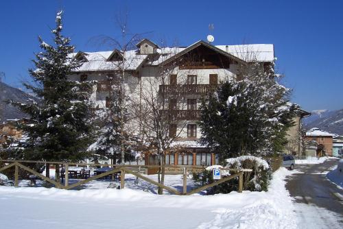 a large building in the snow with trees and a fence at Hotel alle Rose in Cavedago