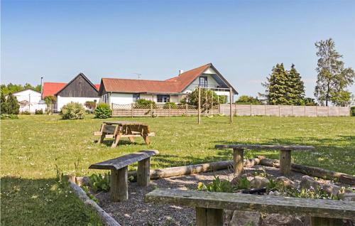 a group of picnic tables in a field with a house at Amazing Home In Klemensker With Wifi in Klemensker