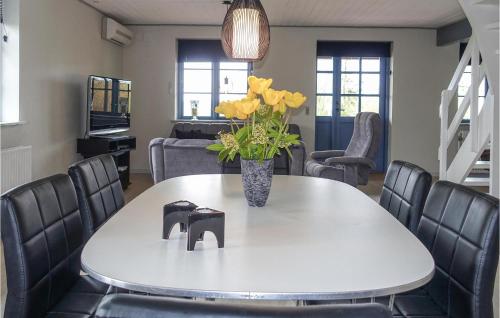 a white table with a vase of yellow flowers on it at Amazing Home In Klemensker With Wifi in Klemensker