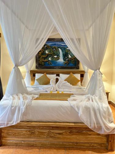 a bed with white sheets and a canopy at Royal Amertha Ubud Jungle View in Gianyar