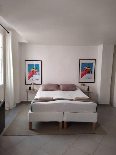 - une chambre blanche avec un lit et deux photos sur le mur dans l'établissement MY COSY - Appartement Vieux Nice, à Nice
