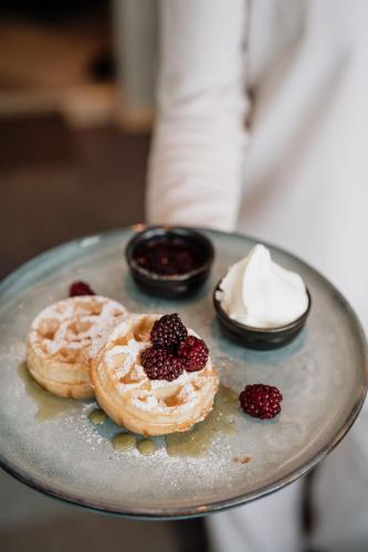 a plate with two donuts with berries and whipped cream at Bohusgården Hotell & Konferens in Uddevalla
