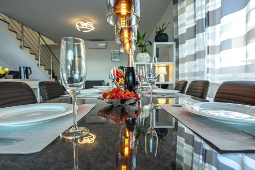a dining table with glasses and a bottle of wine at Luxury White Sails Villas with a Multi Sport Court #2026# and Sea View in Pinezici