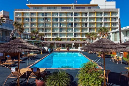 a hotel with a swimming pool with chairs and umbrellas at El Tropicano Riverwalk in San Antonio