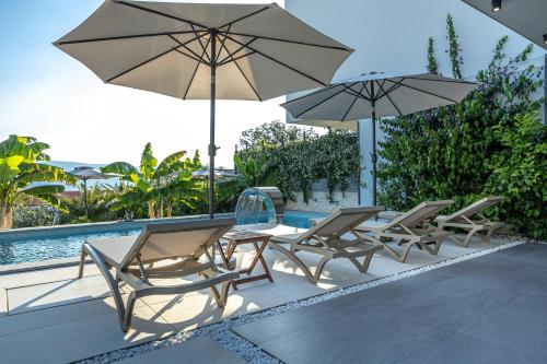 a group of chairs and umbrellas next to a pool at Luxury White Sails Villas with a Multi Sport Court #2026# and Sea View in Pinezici