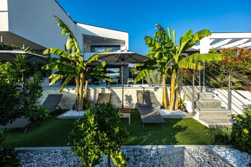 a house with a yard with chairs and palm trees at Luxury White Sails Villas with a Multi Sport Court #2026# and Sea View in Pinezici