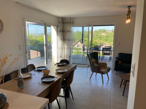 une salle à manger avec une table et des chaises et un balcon dans l'établissement Villa Perle du Rouergue, à Villefranche-de-Rouergue