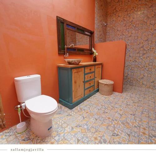 an orange bathroom with a toilet and a sink at Villa Amador by Suasana Villa in Jarakan