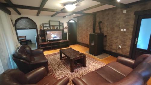 a living room with leather furniture and a flat screen tv at Gorska Vila Sisevac in Sisevac