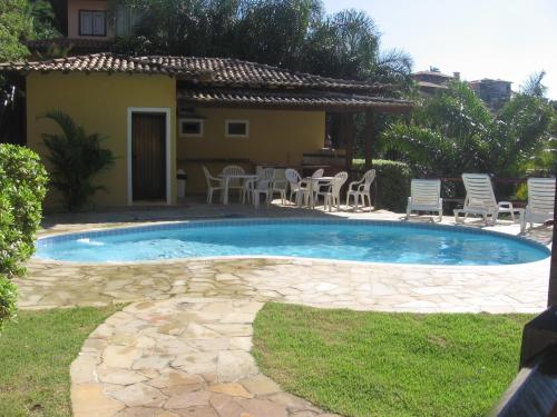 una piscina en un patio con sillas y una casa en BUZIOS CASA POR doSOL noMAR PRAIA ePISCINA, en Búzios