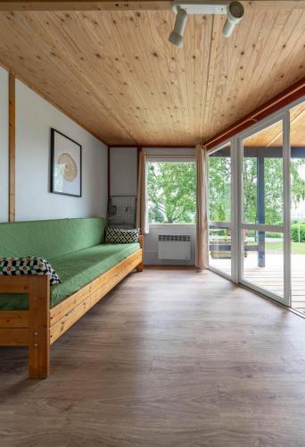 a bedroom with a green bed and large windows at Camping Le Mont Libre - Cottage & espace nature - Gannat in Gannat