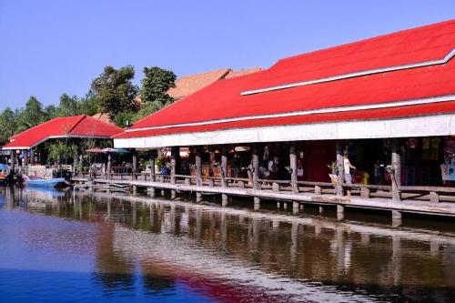 a building with a red roof next to a body of water at Greenfield Valley Fishing Resort in Hua Hin