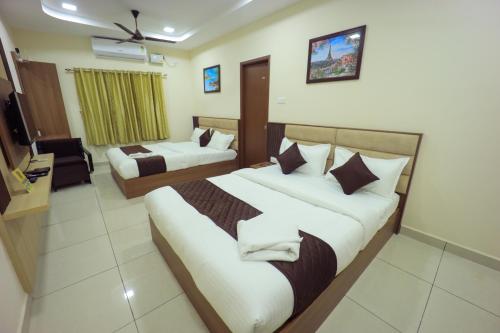 a hotel room with two beds and a television at JKInn in Vellore